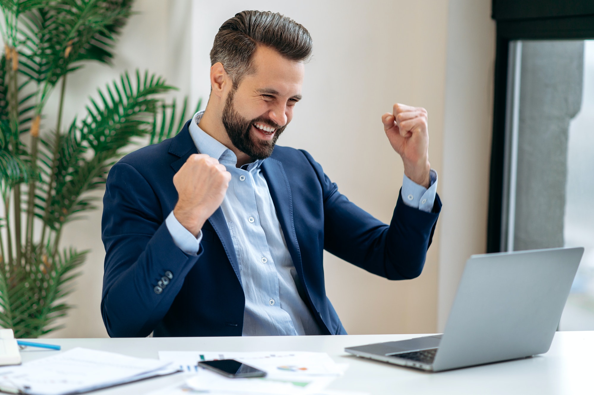 Successful joyful lucky caucasian businessman in a suit, ceo company, manager, sits at work desk in